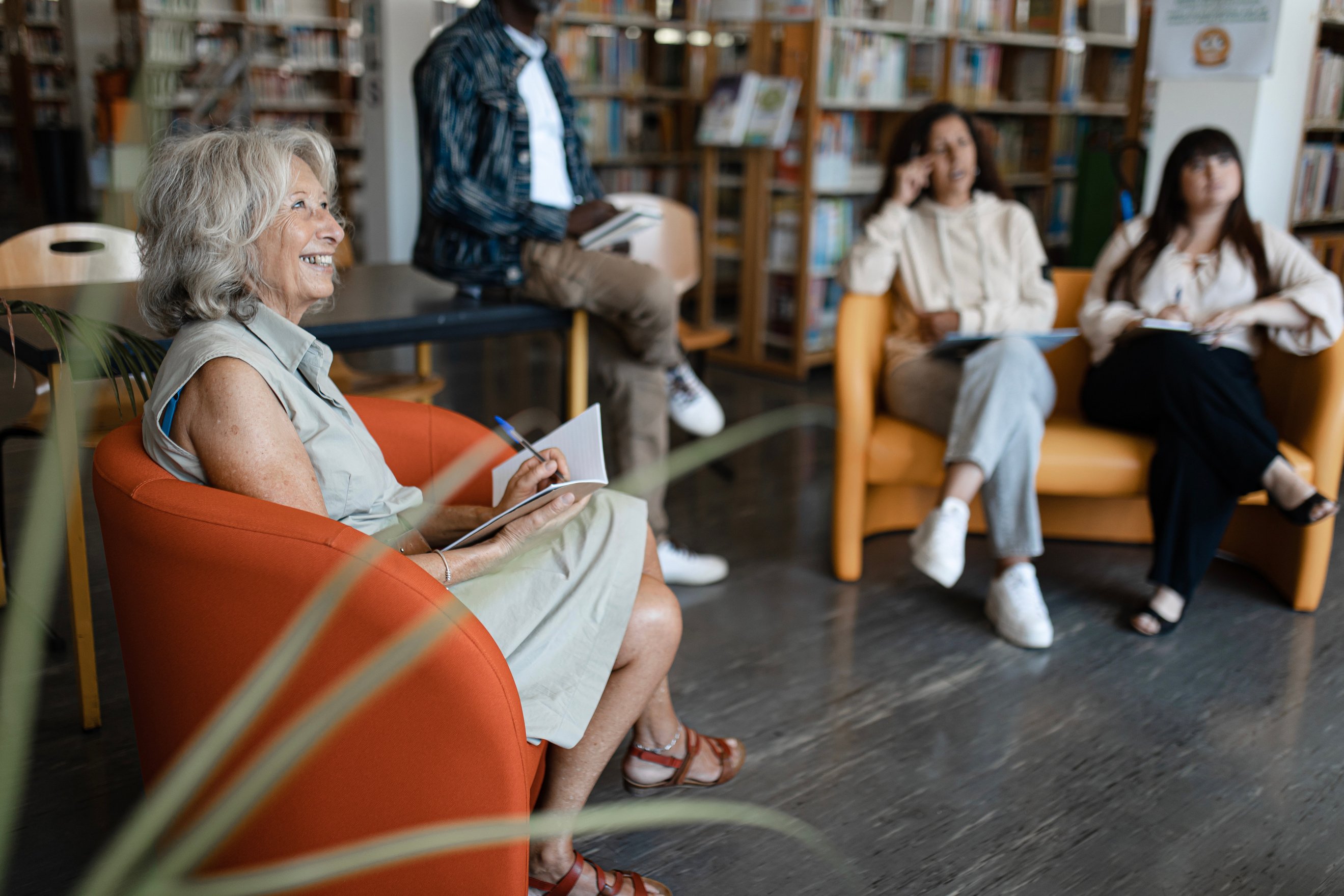 a group of people sitting in chairs in a library taking notes during a training.