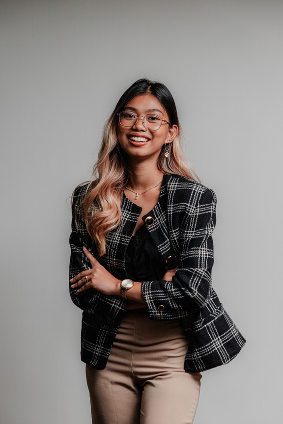 an individual smiling, wearing glasses and a plaid jacket